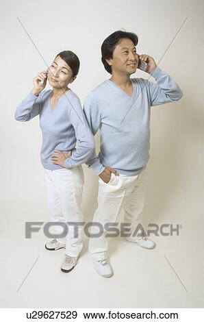 Stock Photo - Mature couple talking on mobile phones. Fotosearch