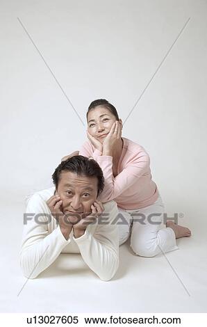 Stock Photography - Mature man lying on front, mature woman sitting next to him. Fotosearch