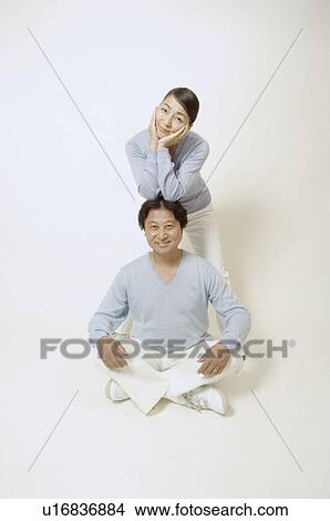 Mature man sitting cross-legged, mature woman behind him View Large Photo Image Picture - Mature man sitting cross-legged, mature woman behind him. Fotosearch
