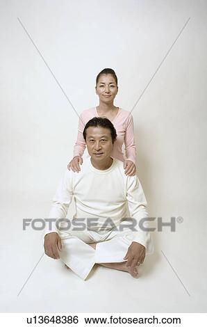 Stock Photograph - Mature man sitting cross-legged, mature woman behind him. Fotosearch