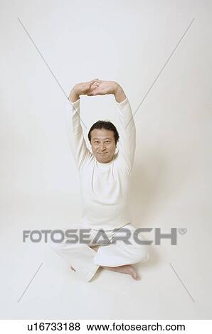Stock Photo - Mature man sitting on floor stretching. Fotosearch