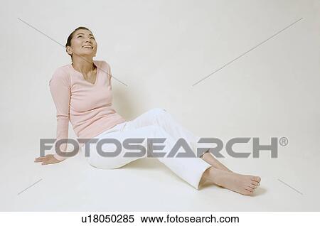 Stock Photography - Mature woman sitting on floor smiling. Fotosearch