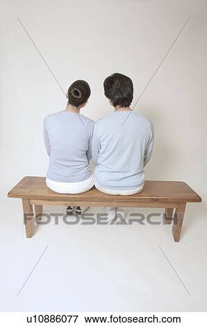 Stock Photo - Rear view of mature couple sitting on bench. Fotosearch