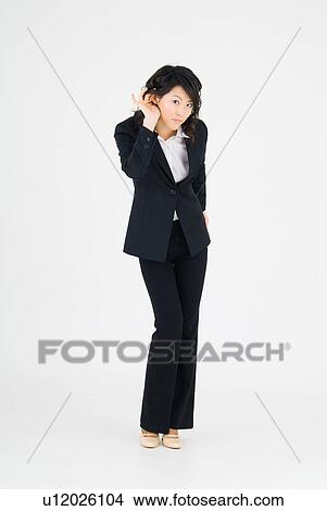 Picture - Young woman listening, hand behind ear. Fotosearch