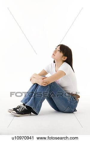 Stock Image - Young woman sitting and looking up. Fotosearch