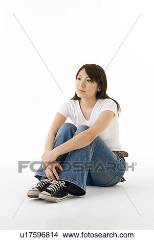 Picture - Young woman sitting, hugging knees. Fotosearch