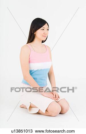 Stock Image - Young woman sitting on floor. Fotosearch