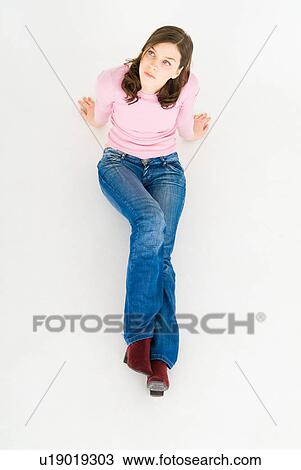 Stock Image - Young woman sitting on floor. Fotosearch