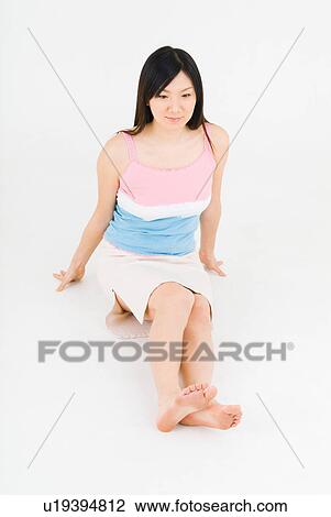 Stock Image - Young woman sitting on floor. Fotosearch