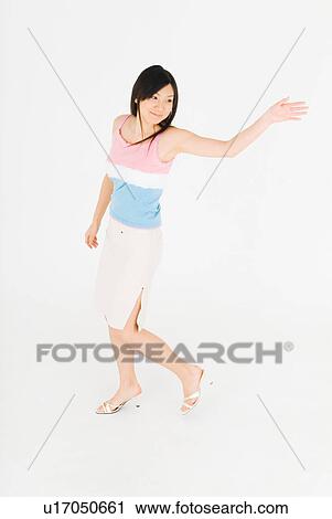 Stock Image - Young woman walking, waving hand. Fotosearch