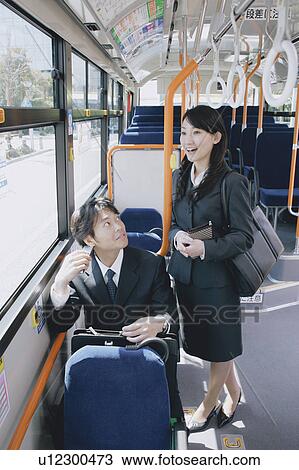 Stock Image - A young woman and a mid adult man talking in a bus. Fotosearch