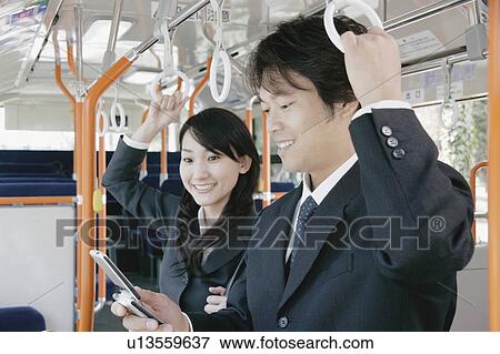 Stock Photo - A young woman and a mid adult man talking in a bus. Fotosearch