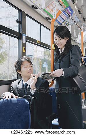 Stock Photography - A young woman and a mid adult man talking in a bus. Fotosearch