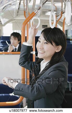 Stock Photo - A young woman checking watch in a bus. Fotosearch