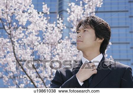 Stock Photo - Mid adult man adjusting tie. Fotosearch