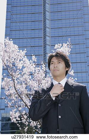 Stock Photo - Mid adult man adjusting tie. Fotosearch