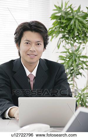 Stock Photograph - Mid adult man working in office. Fotosearch