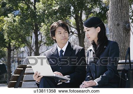 Young woman and mid adult man sitting on bench View Large Photo Image Stock Photo - Young woman and mid adult man sitting on bench. Fotosearch
