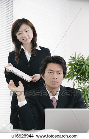 Young woman handing document to her boss View Large Photo Image Picture - Young woman handing document to her boss. Fotosearch
