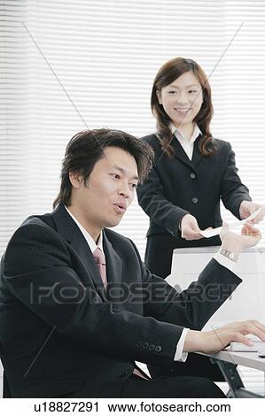 Young woman handing document to her boss View Large Photo Image Stock Image - Young woman handing document to her boss. Fotosearch