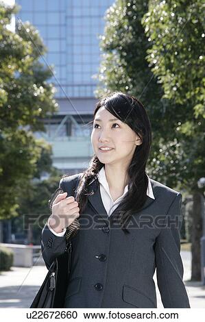 Stock Image - Young woman in suit walking on street. Fotosearch