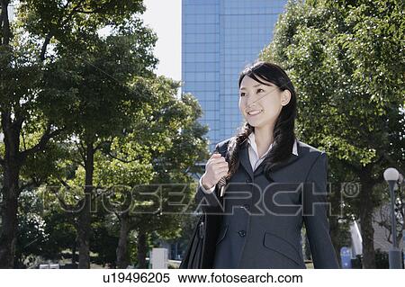 Stock Photography - Young woman in suit walking on street. Fotosearch