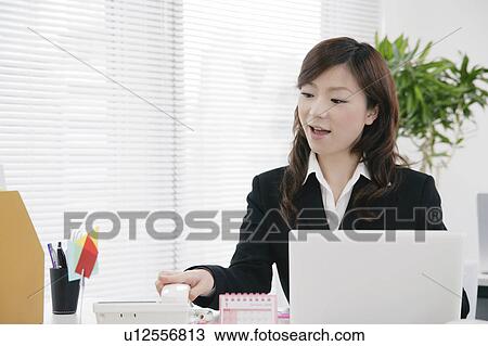 Stock Image - Young woman taking phone call. Fotosearch