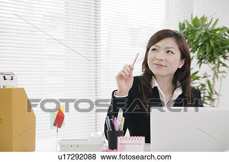 Stock Photo - Young woman thinking at her desk. Fotosearch