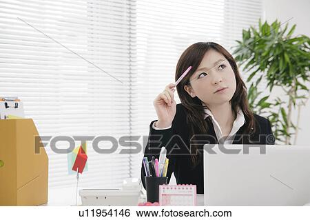 Stock Photograph - Young woman thinking at her desk. Fotosearch