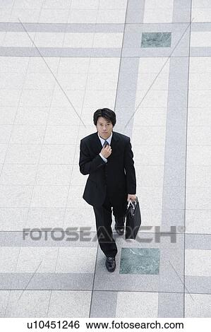 A mid adult businessman adjusting tie View Large Photo Image Stock Photograph - A mid adult businessman adjusting tie. Fotosearch