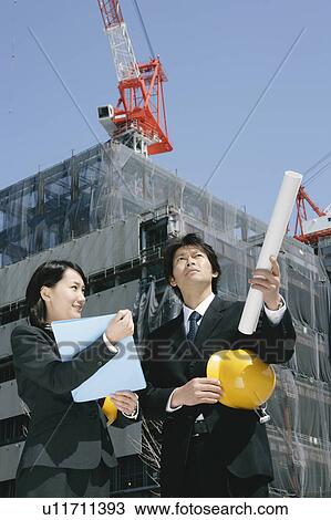 A mid adult businessman and young businesswoman talking at construction site View Large Photo Image Stock Image - A mid adult businessman and young businesswoman talking at construction site. Fotosearch