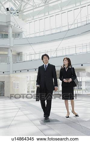 Stock Photography - A mid adult businessman and young businesswoman walking. Fotosearch
