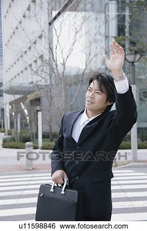 Stock Photograph - A mid adult businessman hailing a taxi. Fotosearch