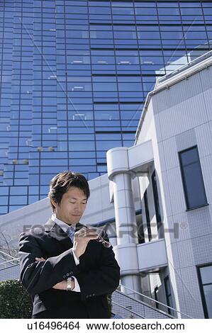 Picture - A mid adult businessman looking at glasses. Fotosearch