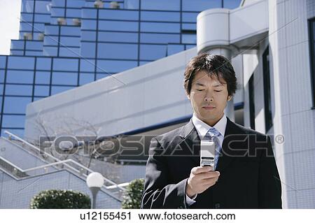 Stock Image - A mid adult businessman looking at mobile phone. Fotosearch