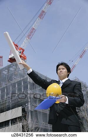 Stock Photograph - A mid adult businessman standing at construction site. Fotosearch