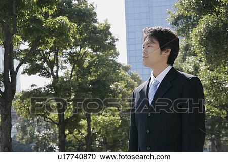 Stock Image - A mid adult businessman standing. Fotosearch