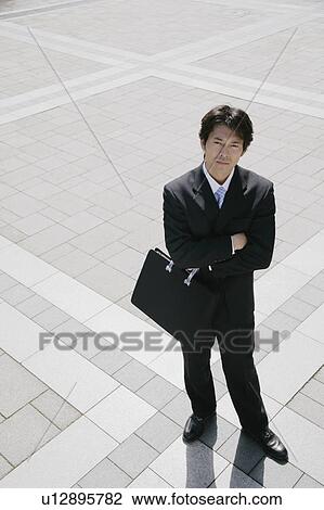 Stock Image - A mid adult businessman standing with his arms crossed. Fotosearch