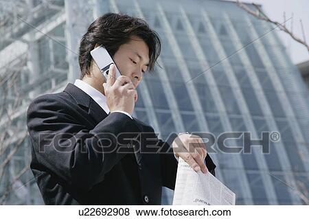 Stock Photo - A mid adult businessman talking over a mobile phone. Fotosearch