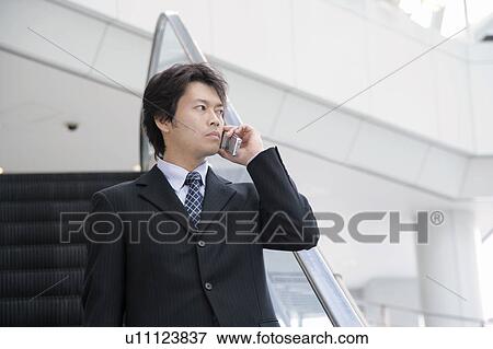 Stock Photo - A mid adult businessman talking over mobile phone. Fotosearch