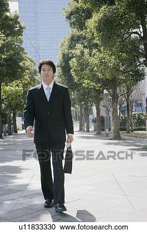 Stock Image - A mid adult businessman walking. Fotosearch
