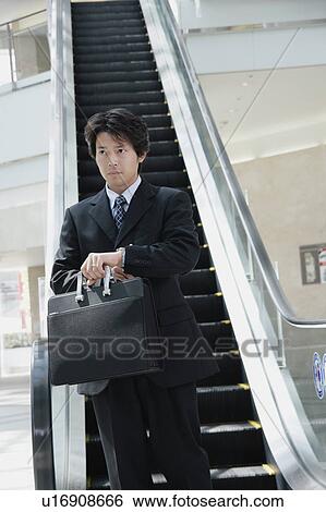 Stock Photograph - A mid adult man going down escalator. Fotosearch
