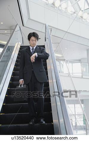Stock Image - A mid adult man looking at watch. Fotosearch