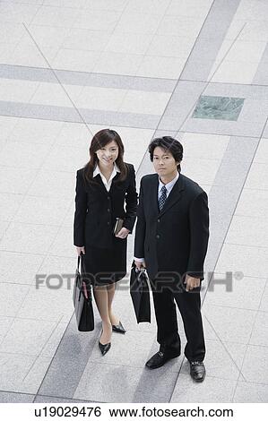 A young businesswoman and mid adult businessman standing View Large Photo Image Stock Photograph - A young businesswoman and mid adult businessman standing. Fotosearch