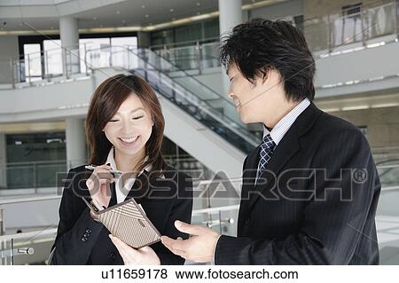 Stock Photo - A young woman and a mid adult man talking in lobby. Fotosearch