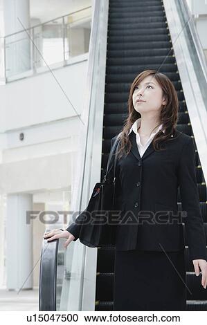 Stock Image - A young woman in suit looking up. Fotosearch