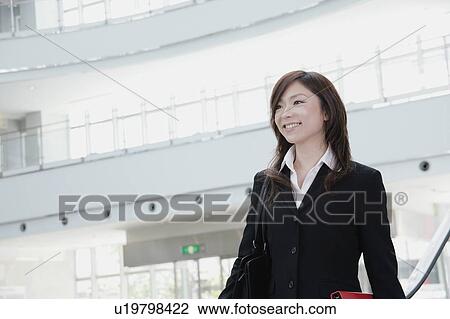 Stock Image - A young woman in suit smiling. Fotosearch