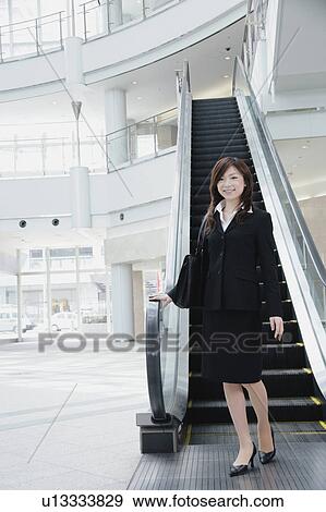 A young woman in suit standing in front of escalator View Large Photo Image Stock Photo - A young woman in suit standing in front of escalator. Fotosearch