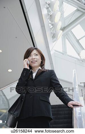 Picture - A young woman talking over mobile phone. Fotosearch