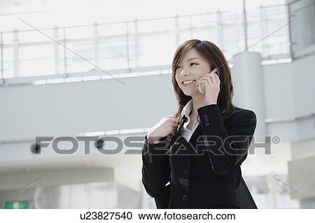 Stock Image - A young woman talking over mobile phone. Fotosearch